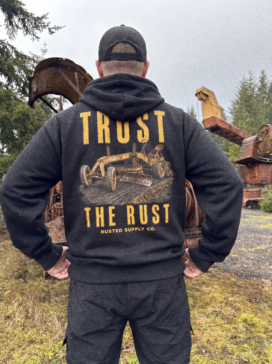 Operator wearing the TRUST THE RUST motor grader hoodie on a jobsite