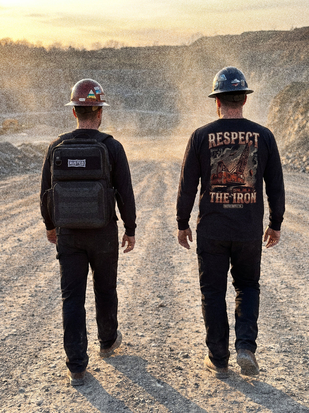 Two tradesmen walking a quarry haul road, one wearing the RUSTED Crew Pack