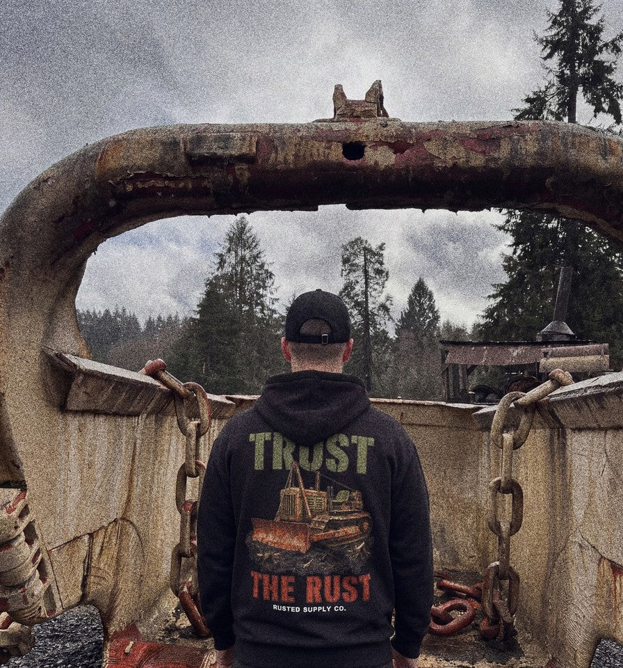 TRUST THE RUST cable dozer hoodie worn by an operator on a jobsite