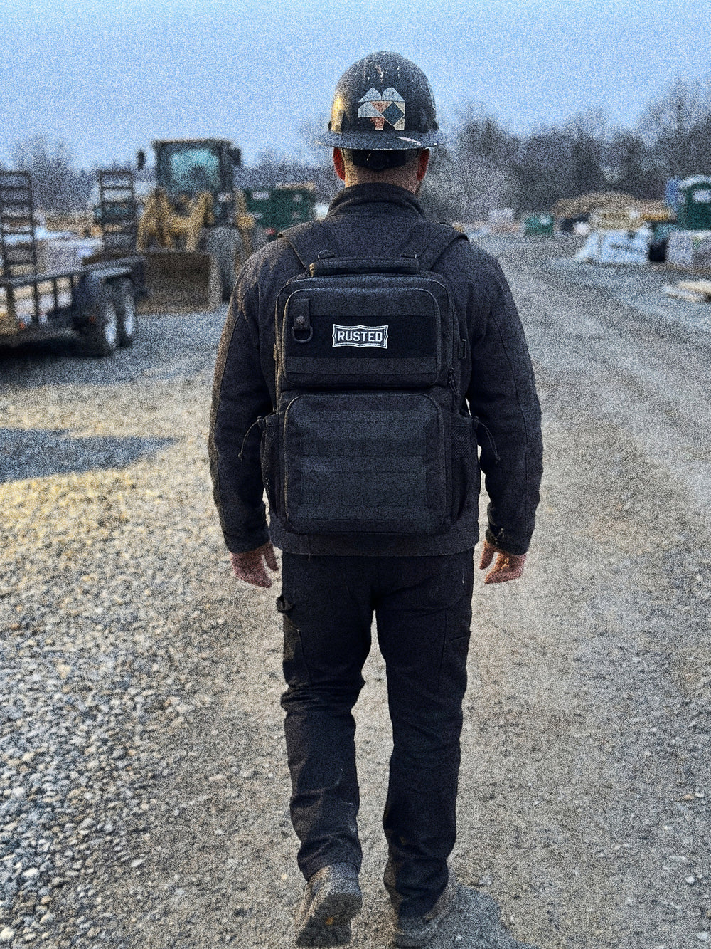 Tradesman wearing the RUSTED Crew Pack walking onto a job site at first light